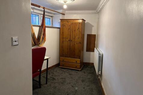 A cozy bedroom featuring a wooden wardrobe, a w...