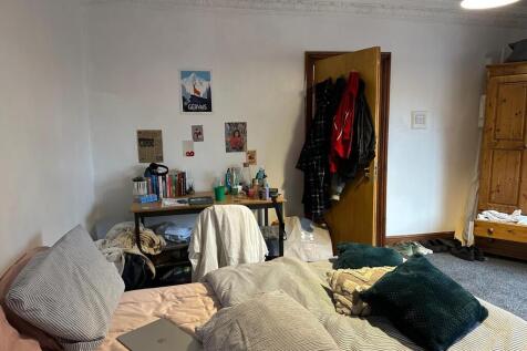 A cozy bedroom featuring a bed, desk, and perso...