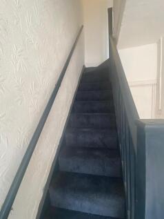 A narrow staircase featuring dark carpeted step...