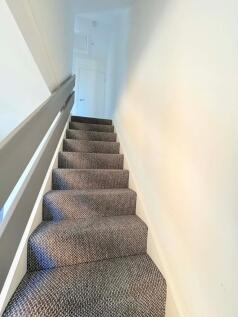 Carpeted internal staircase with modern grey ha...