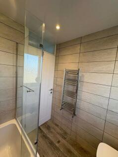Modern tiled bathroom with a bath and glass sho...