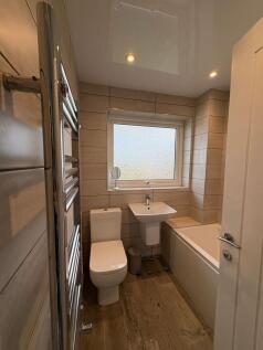 Modern, tiled bathroom with a white toilet, ped...