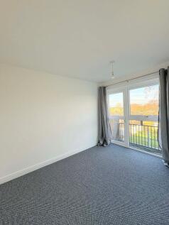 Bright, neutral bedroom with large windows and ...