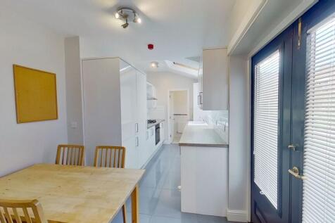 Bright, modern galley kitchen with white cabine...