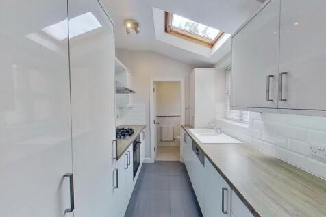Bright, modern galley kitchen with sleek white ...