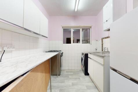 Bright galley kitchen with white cabinets, marb...