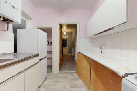 Long galley kitchen with light cabinetry, tiled...
