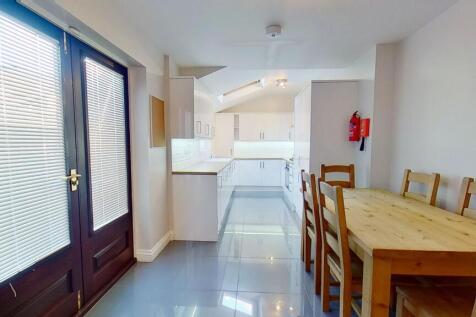 Bright modern galley kitchen and dining area wi...