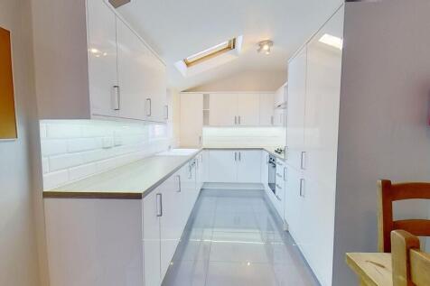 Bright, modern galley kitchen with high-gloss w...