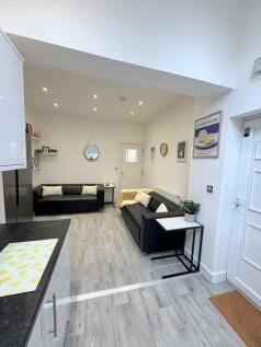 Bright, modern living area with two black sofas...