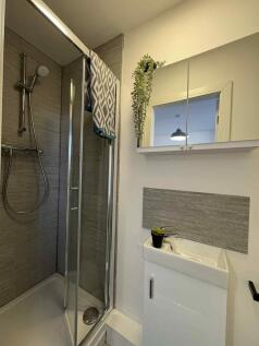 Modern compact bathroom with a tiled shower enc...
