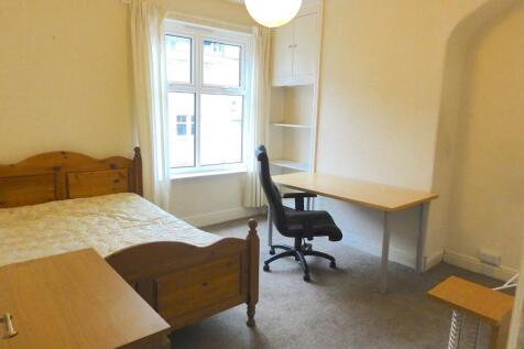 A cozy bedroom featuring two wooden beds, a win...