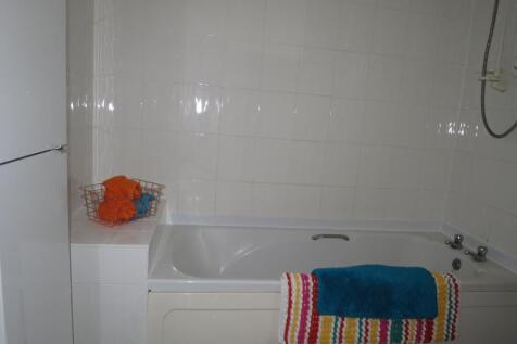 Tiled bathroom featuring a built-in bathtub wit...