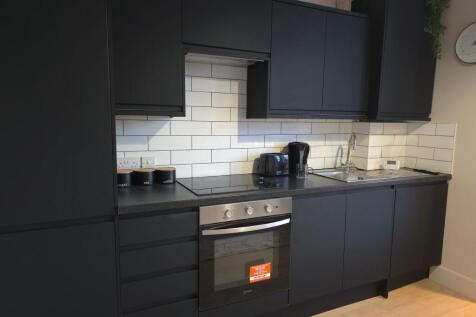 Modern fitted kitchen with sleek dark cabinets,...