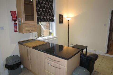 Compact open-plan kitchen area with a black sto...