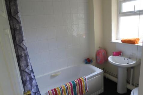 Bright, tidy bathroom with a white bathtub and ...