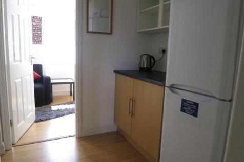 Compact kitchen area with wood-effect cabinets,...
