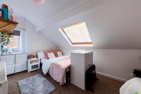 Bright, cozy attic bedroom with a sloped ceilin...