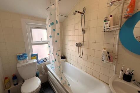 Compact bathroom with a shower-over-bath, patte...