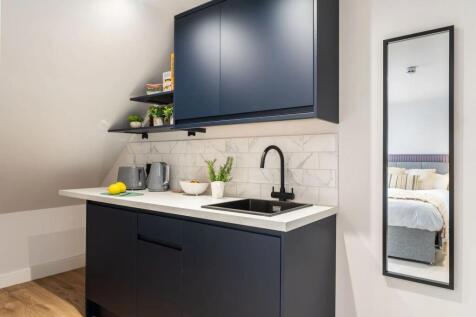 Modern kitchen featuring sleek navy cabinetry, ...