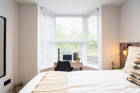A bright and airy bedroom featuring a large win...