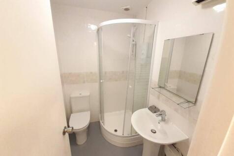 Bright, modern bathroom with a curved glass sho...