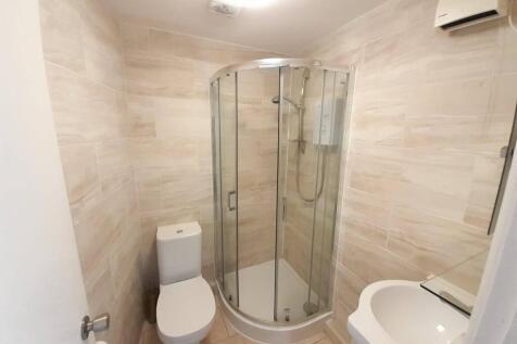 Bright, modern bathroom with a curved glass sho...