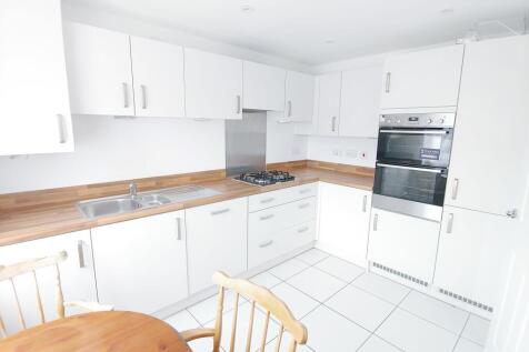 Bright modern kitchen with white cabinets, wood...