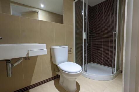 Modern tiled bathroom with a corner glass showe...