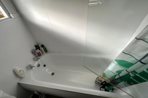 A bright and tidy bathroom featuring a bathtub ...