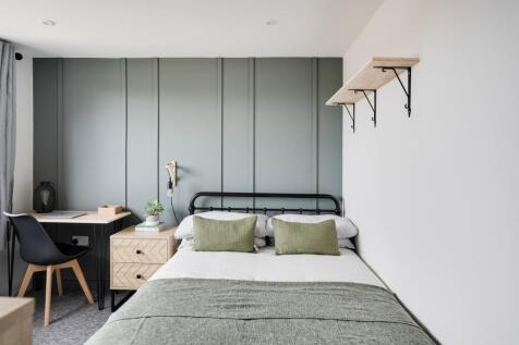 A clean and well-lit double bedroom with a desk...