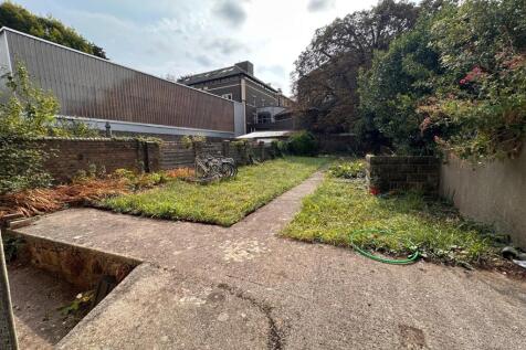 Sunny private rear garden with a central paved ...
