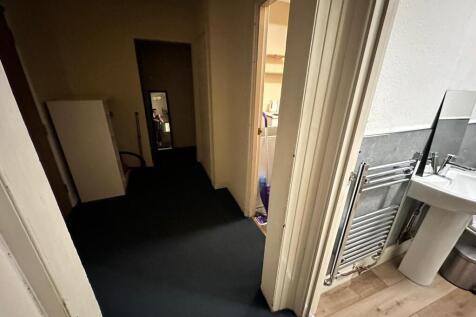 Narrow interior hallway with dark carpet leadin...