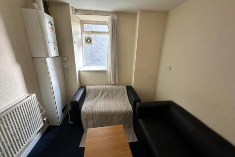 Cosy communal lounge with two black sofas, a sm...