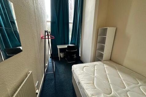 Bright single bedroom with tall windows, teal c...