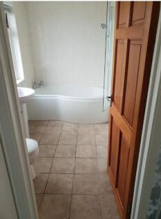 A bright and tidy bathroom featuring a bath and...