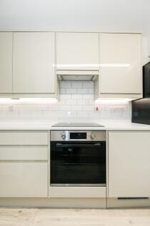 A modern, tidy kitchen featuring white cabinetr...