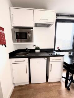 Compact modern kitchenette with white cabinetry...