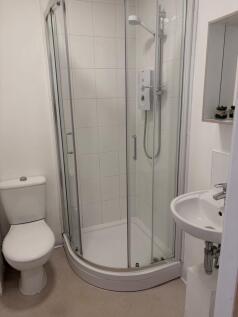 Bright, modern bathroom with a curved glass sho...