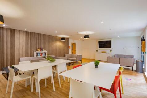 Bright, modern communal lounge with large white...