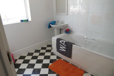 Bright, tiled bathroom with a bathtub and showe...