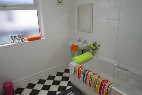Bright, clean bathroom with a white tiled bath ...