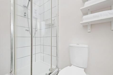 Bright, modern bathroom with a tiled corner sho...