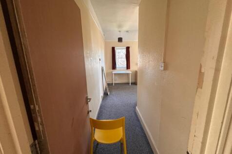 Long internal hallway with neutral walls, fitte...