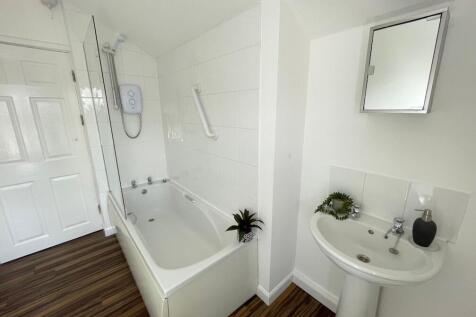 Bright, modern bathroom with a fitted bath and ...