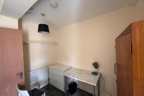 Compact furnished single bedroom with a desk, c...