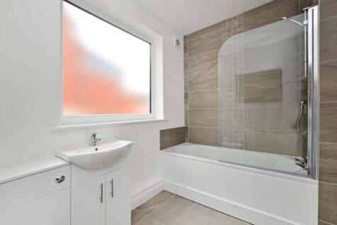 Bright, modern bathroom with a tiled shower-ove...