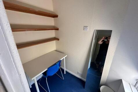 Compact room with a study desk, shelving and a ...