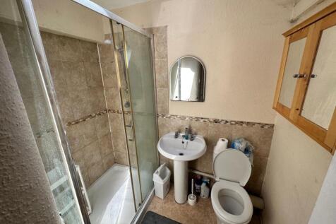 Bright tiled bathroom with a glass-enclosed sho...