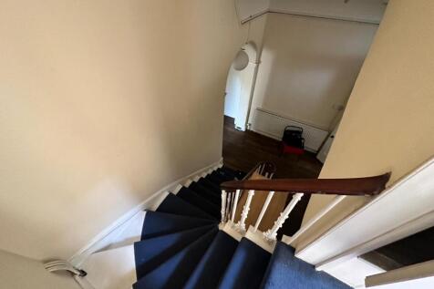 Curved carpeted staircase with white spindles a...